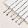 Finished stainless steel sparkle chain necklaces with lobster clasps laid neatly on a white textured stone surface for B2B supplier web site.
