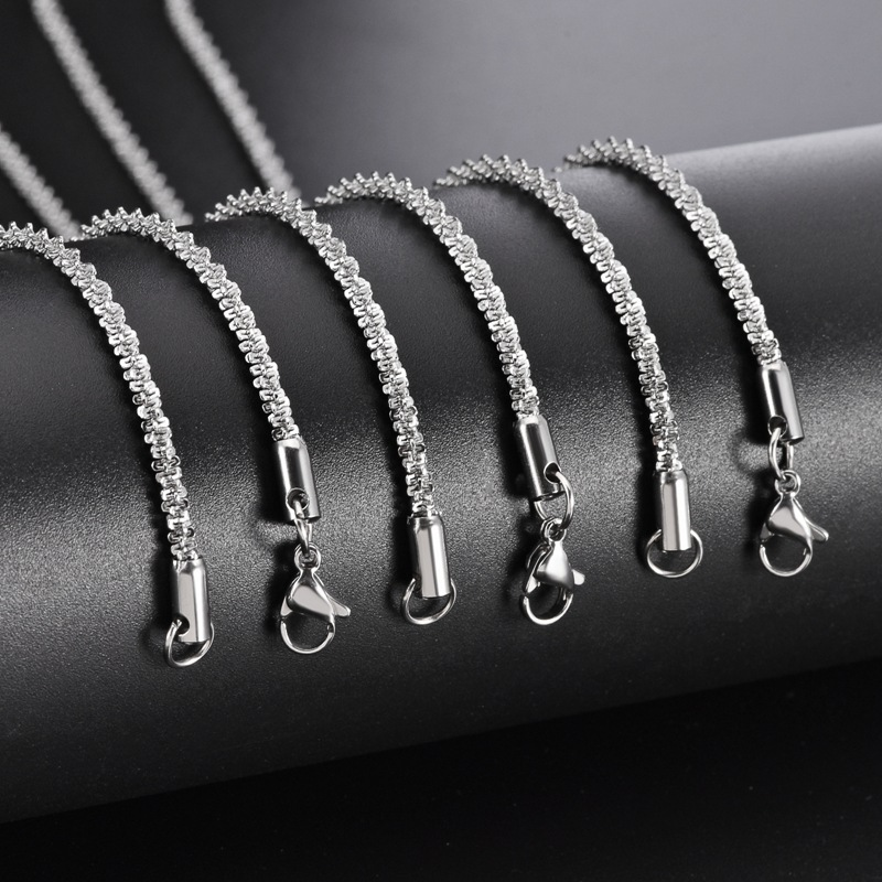 Detailed view of multiple silver stainless steel criss-cross glimmer chain necklaces showing the sturdy lobster clasps and smooth end connectors.