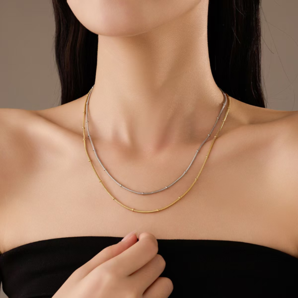 PAO`Y64S5F1M{IQ2UU9@~`W Model wearing a trendy layered set of silver and gold stainless steel satellite snake chain necklaces highlighting the sleek minimalist aesthetic.