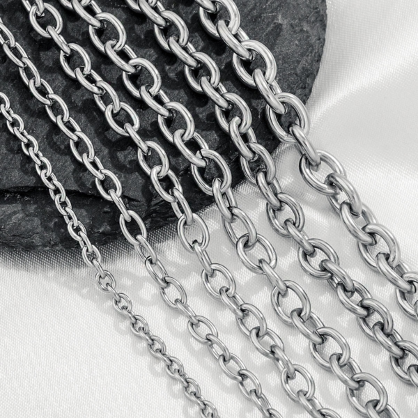 Multi-size stainless steel O-chains and cable link chains arranged neatly on a dark stone background for B2B supplier catalog.