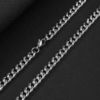 Detailed view of a high-quality finished silver stainless steel curb chain necklace with a secure lobster clasp on a dark textured background for B2B supplier.