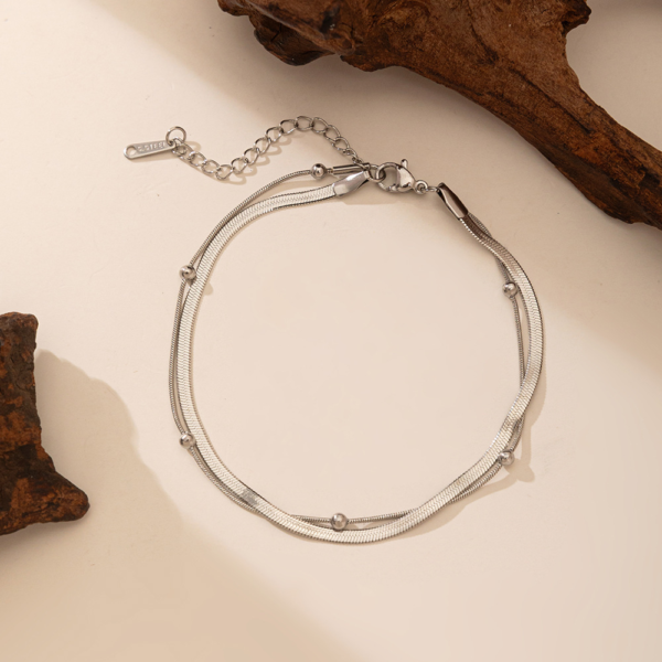 双层不锈钢扁蛇骨链+夹珠圆蛇链 (2) A finished silver stainless steel double layer flat snake and bead chain bracelet layout with a lobster clasp for B2B supplier shop.