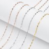 Finished stainless steel shimmering sequin chains in gold, steel silver, and rose gold finishes neatly draped over a white cylindrical column.