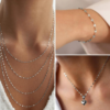 Lifestyle layout of a model wearing a layered set of silver stainless steel lip chain necklaces and a matching dainty bracelet on a wrist.
