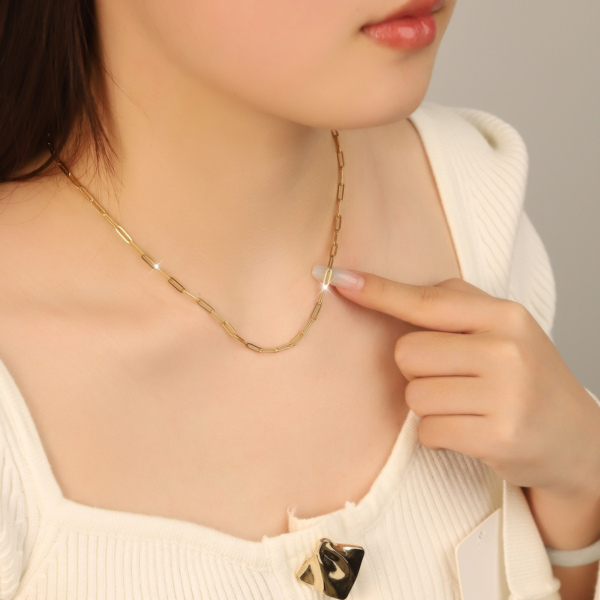 回型链 (2) Model wearing a minimalist gold stainless steel paperclip necklace on a black mannequin, with an inset showing the matching bracelet on a wrist.