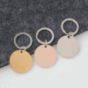 圆形钥匙扣 (1) Wholesale blank round disc stainless steel keychains in gold, rose gold, and silver finishes arranged neatly on a dark felt background for B2B supplier.