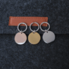 圆形钥匙扣 (3) Parallel display of bulk customized stainless steel round stampings in rose gold, yellow gold, and silver finishes hanging against a dark fabric backdrop.