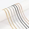 圆蛇链 (9) Wholesale finished stainless steel snake chain necklaces in gold, mirror silver, and matte black draped fluidly over a white cylindrical stage.