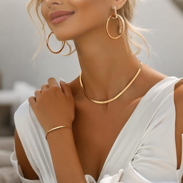 扁蛇链 Flat snake chain (11) Model wearing luxury 18K gold plated stainless steel herringbone necklace and bracelet set paired with hoop earrings for B2B shop layout.
