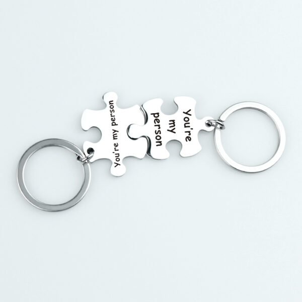拼图钥匙扣 (12) Wholesale finished silver stainless steel interlocking puzzle piece couple keychains engraved with "You're my person" on a clean background.
