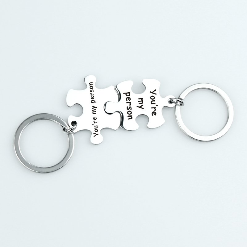 拼图钥匙扣 (12) Wholesale finished silver stainless steel interlocking puzzle piece couple keychains engraved with "You're my person" on a clean background.