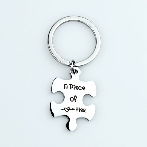 拼图钥匙扣 (20) An isolated view of a single blank stainless steel puzzle piece keychain custom engraved with "A Piece of Her" and a small heart icon.