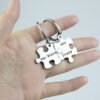 拼图钥匙扣 (6) A close-up view of fingers holding a pair of interlocking stainless steel puzzle keychains showing the precise seamless snapping mechanism.