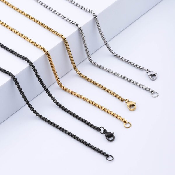 Steel-tone, gold-tone, and black box chains featuring lobster clasps are displayed in a straight line against a white background, allowing B2B buyers to compare the options and examine the details.