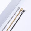 Steel-tone, gold-tone, and black box chains featuring lobster clasps are displayed in a straight line against a white background, allowing B2B buyers to compare the options and examine the details.