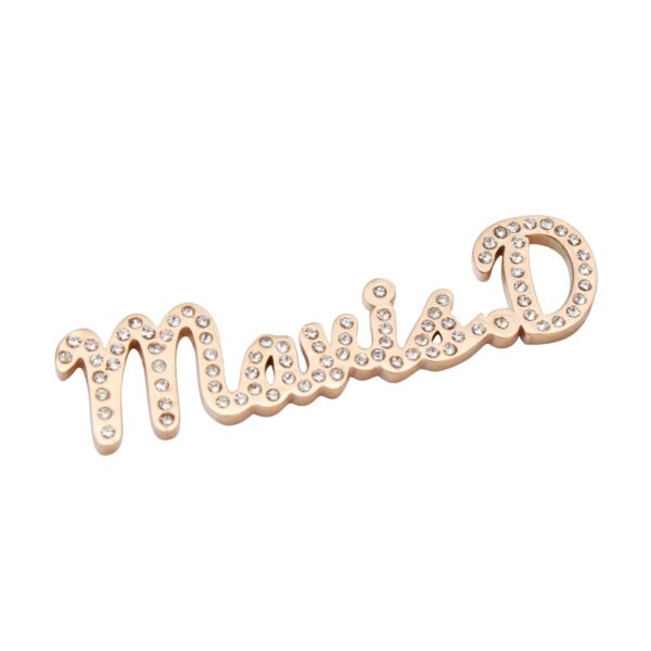 满钻字母胸针 (3) A close-up shot showing a custom rose gold stainless steel name brooch—featuring connected script lettering and set with cubic zirconia—lying flat against a clean white background.