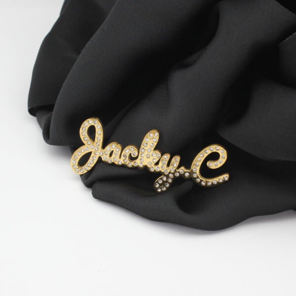 满钻字母胸针 (6) A heavy-duty custom 18K gold plated cursive letter name brooch pinned securely on a black silk cloth highlighting the crystal pave setting.