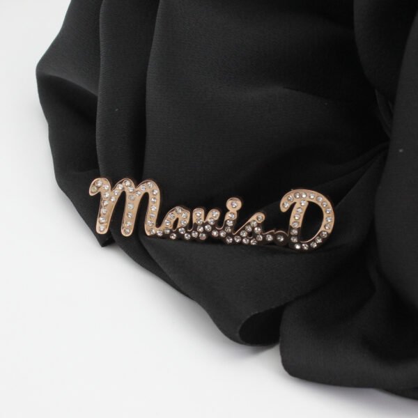 满钻字母胸针 (7) Wholesale personalized rose gold plated stainless steel rhinestone name brooch pinned on a black fabric background for premium retail display.
