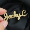 满钻字母胸针 (8) A hand holds a gold, fully stone-encrusted lapel pin featuring a custom-made name in script, showcasing its substantial thickness and the sparkling facets of the zirconia stones.
