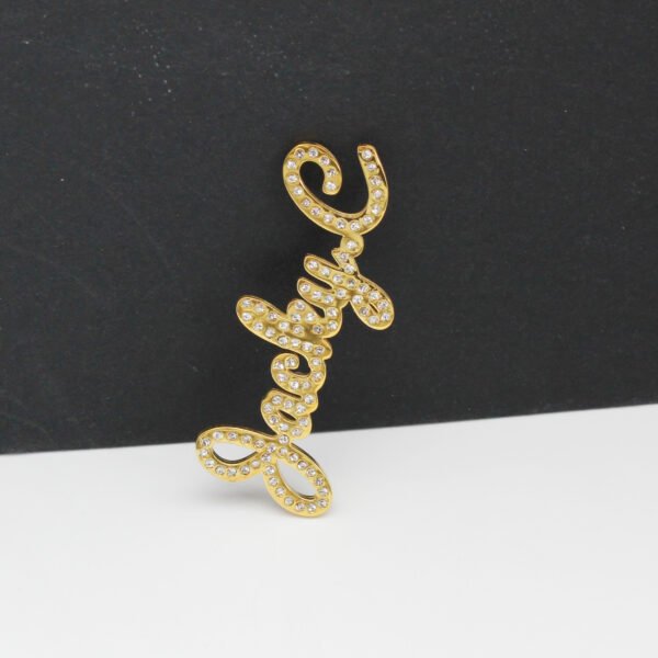 满钻字母胸针 (9) A front view of a custom 18K gold plated stainless steel cursive letter name brooch fully paved with shimmering rhinestones for boutique catalog.
