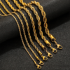 Wholesale gold stainless steel twisted rope chains of various thicknesses displayed elegantly on a dark textured background for B2B supplier.