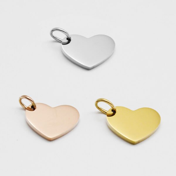 16×12偏孔小心形_0000_图层 8 Wholesale blank heart-shaped metal stamping tags in silver, rose gold, and gold finishes ready for laser engraving on a clean backdrop.