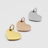 16×12偏孔小心形_0001_图层 7 Three blank mirror polished stainless steel heart charms arranged in a diagonal row in gold, rose gold, and silver for B2B supplier.