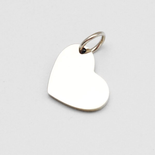 16×12偏孔小心形_0002_图层 5 A blank finished silver stainless steel heart pendant with a secure connection ring laid flat on a clean white backdrop for B2B shop.