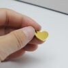 16×12偏孔小心形_0005_图层 1 A close-up view of fingers holding a mini 18K gold plated stainless steel heart tag blank to showcase its compact size and smooth edges.