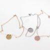 20圆牌和十字链 03 Multiple finished silver, gold, and rose gold round locket necklaces coiled into compact circles next to their chains for B2B supplier shop.