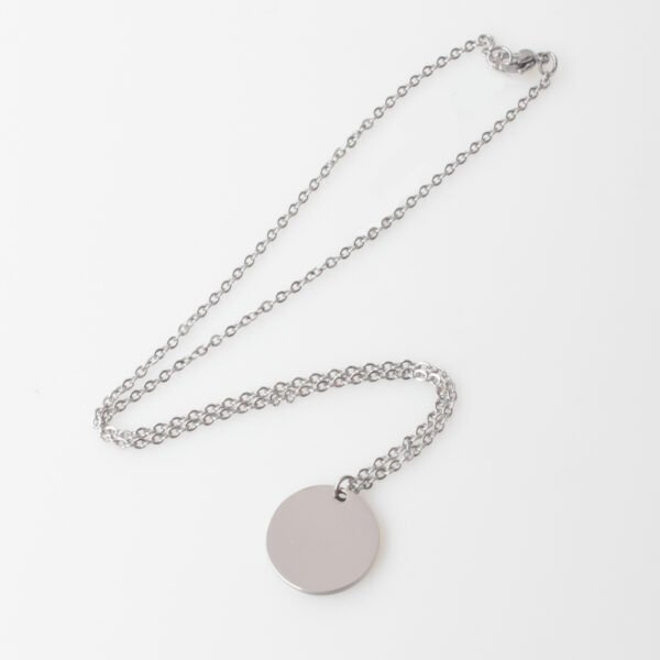 20圆牌和十字链 08 An isolated view of a finished silver stainless steel minimalist round coin pendant necklace flatly laid on a clean white backdrop for B2B catalog.