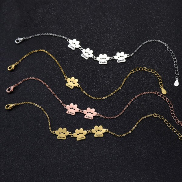 B2B catalog photo showing multiple finished stainless steel paw name bracelets in silver, gold, and rose gold with 1 to 4 customizable linked charms.