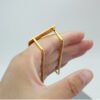 Close-up view of a hand demonstrating the ergonomic parallel bar backing mechanism of a custom gold multi-finger ring.