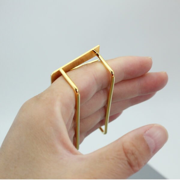 Close-up view of a hand demonstrating the ergonomic parallel bar backing mechanism of a custom gold multi-finger ring.