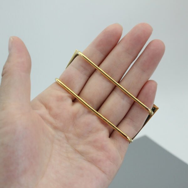 Close-up view of a hand demonstrating the ergonomic parallel bar backing mechanism of a custom gold multi-finger ring.