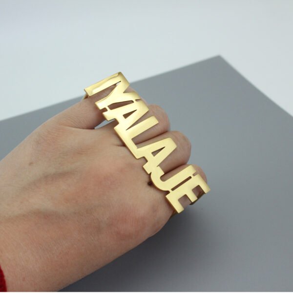 A model wears a custom gold stainless steel multi-finger name ring, showcasing this statement-making, hip-hop-style accessory.