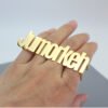 A model wears a custom gold stainless steel multi-finger name ring, showcasing this statement-making, hip-hop-style accessory.