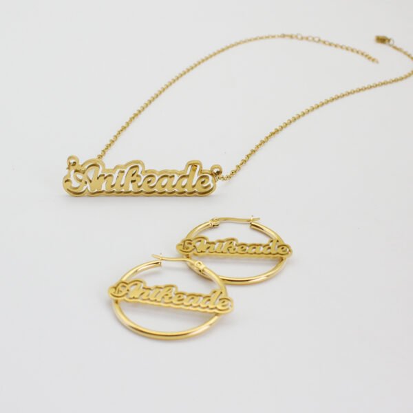 描边项链耳环套装_0002_图层 11 A blank finished 18K gold plated stainless steel personalized 2-layer cursive name necklace and hoop earrings set spelling "Anikeade" on a white background.