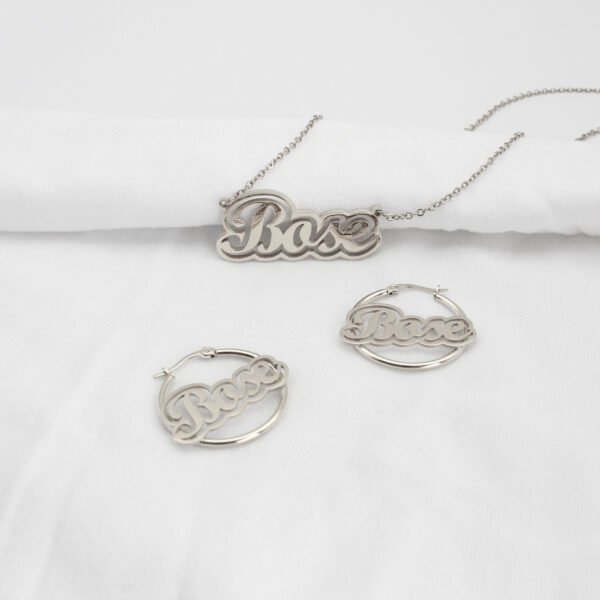 描边项链耳环套装_0010_图层 7 An isolated view of a wholesale finished silver stainless steel custom name jewelry set showing a 3D 2-layer nameplate necklace and matching hoop earrings with the text "Bose".