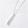 A finished silver stainless steel minimalist vertical 3D block bar chain necklace laid flat with a soft shadow on a clean white backdrop.