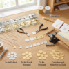 A professional jewelry making workshop displaying stainless steel round discs sorted by processing stages: "To Be Etched", "To Be Punch Stamped", "To Be Polished", and "Complete and Attached to Chain".