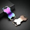 A rainbow anodized and a rose gold stainless steel slide-on collar tag leaning against a textured black box, showing the smooth curved edge profile.