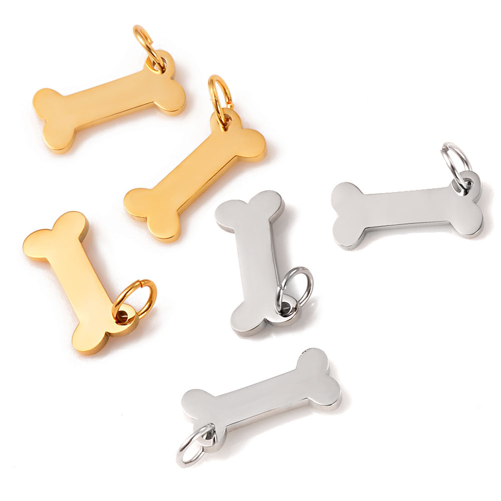 A group of six mini stainless steel bone charms showing a mix of mirror polished silver and gold finishes, arranged elegantly on a white surface.