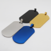 Four heavy-duty stainless steel dog tags in brushed silver, matte black, gold, and blue finishes, arranged overlapping each other on a smooth white surface.