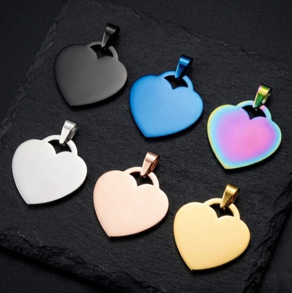 Six heart-shaped stainless steel blank pendants (featuring cut-out hanging holes) are displayed against a dark background; the colors include rainbow, blue, black, rose gold, silver, and gold.