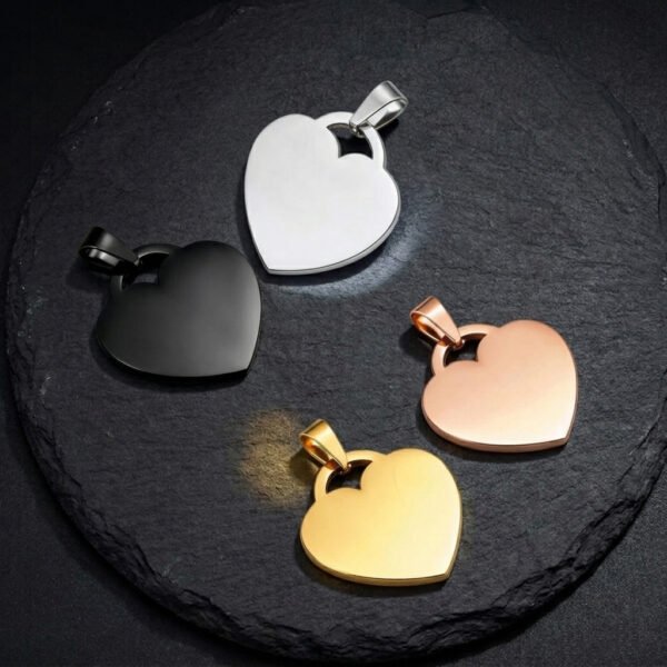 Four polished heart-shaped metal tag blanks in silver, black, gold, and rose gold elegantly placed on a textured black slate stone background with subtle lighting.