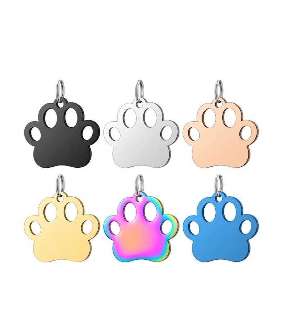 Six colorful stainless steel paw print tags arranged in two rows showing black, silver, rose gold, gold, rainbow, and blue finishes.