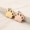 Premium gold and rose gold stainless steel paw print jewelry blanks leaning against a marble block.