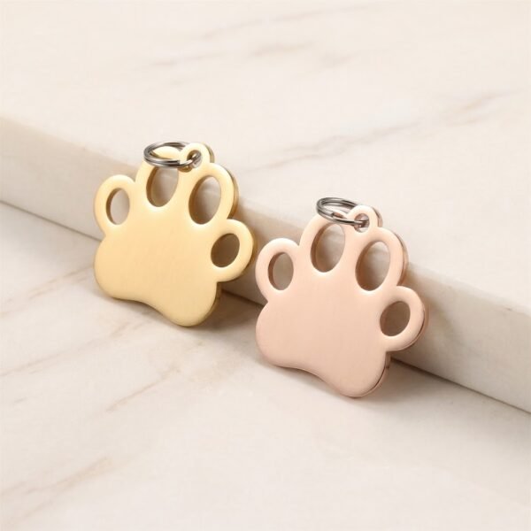 Premium gold and rose gold stainless steel paw print jewelry blanks leaning against a marble block.