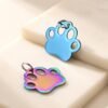 Vibrant blue and rainbow anodized stainless steel paw-shaped charms for custom pet ID tags and keychains.
